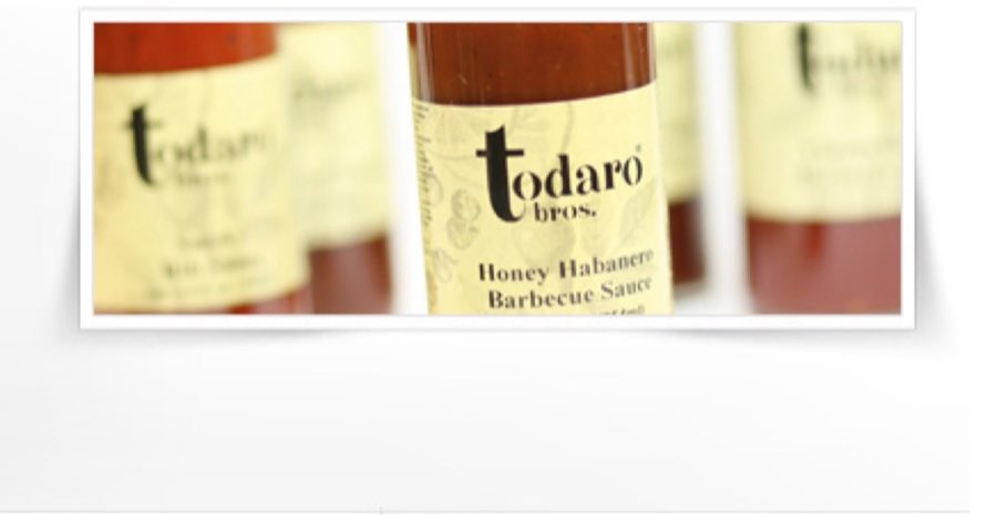 Close-up of Todaro Bros.–branded bottles of Honey Habanero Barbecue Sauce, cream labels with the black todaro bros. wordmark, warm still-life lighting