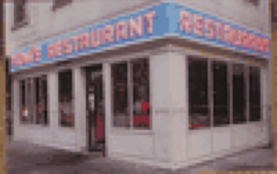 Tom's Restaurant storefront by day, cream facade and blue RESTAURANT lettering on the corner of Broadway