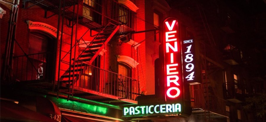 Veniero's vertical red neon sign reading VENIERO and SINCE 1894, glowing above a green neon PASTICCERIA awning on East 11th Street at night