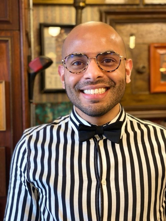 Juan Roberto, York Barbershop stylist, in a black and white striped shirt and bow tie